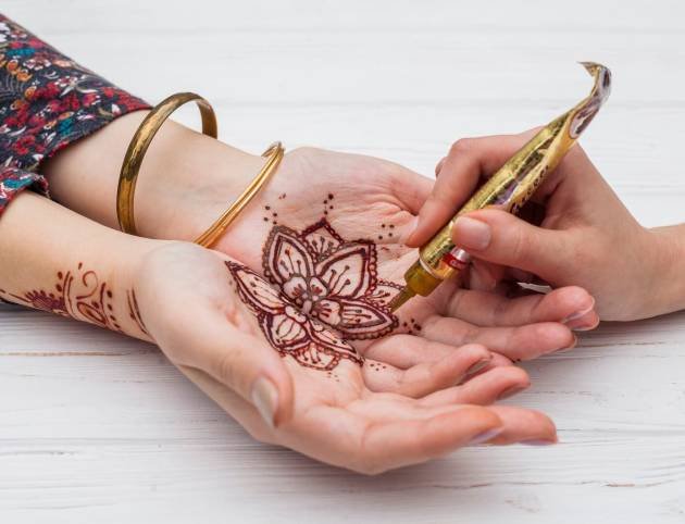 artist-making-mehndi-womans-palms